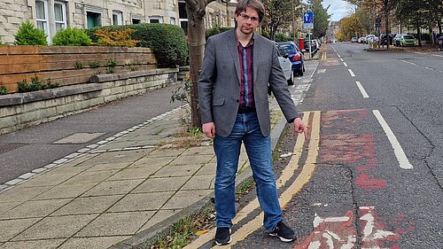 A man pointing at a worn away bicycle lane on McDonald Road