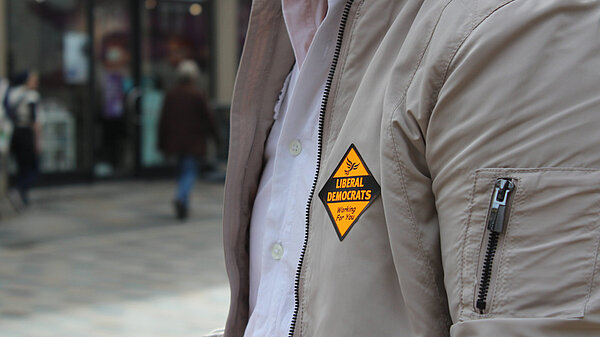 A person's jacket, displaying an orange Liberal Democrat sticker