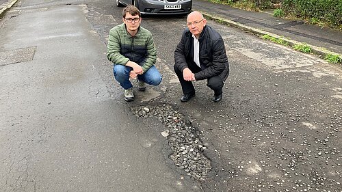 councillors pointing at potholes