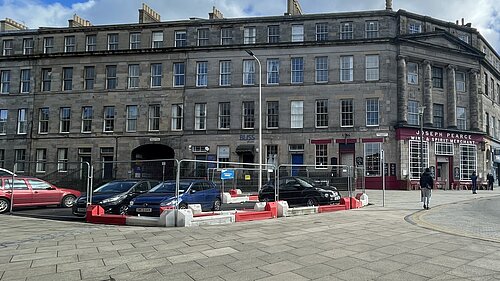 Fencing at the end of a street with cars parked