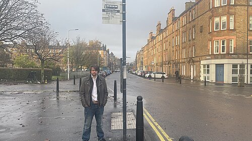 Jack Caldwell standing under a bus stop sign on Dalmeny Street